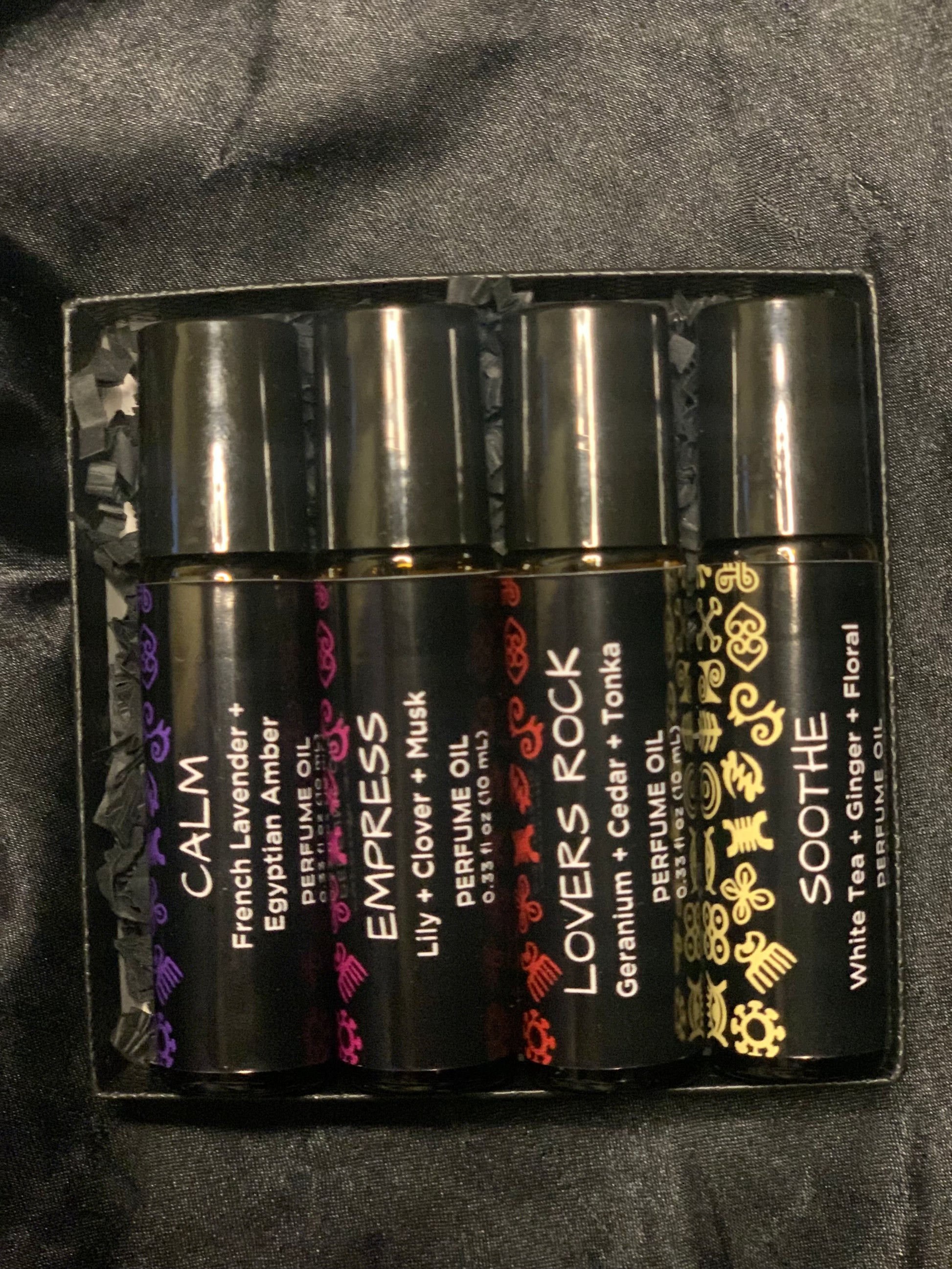 Set of four perfume bottles in a black packaging case on a dark background