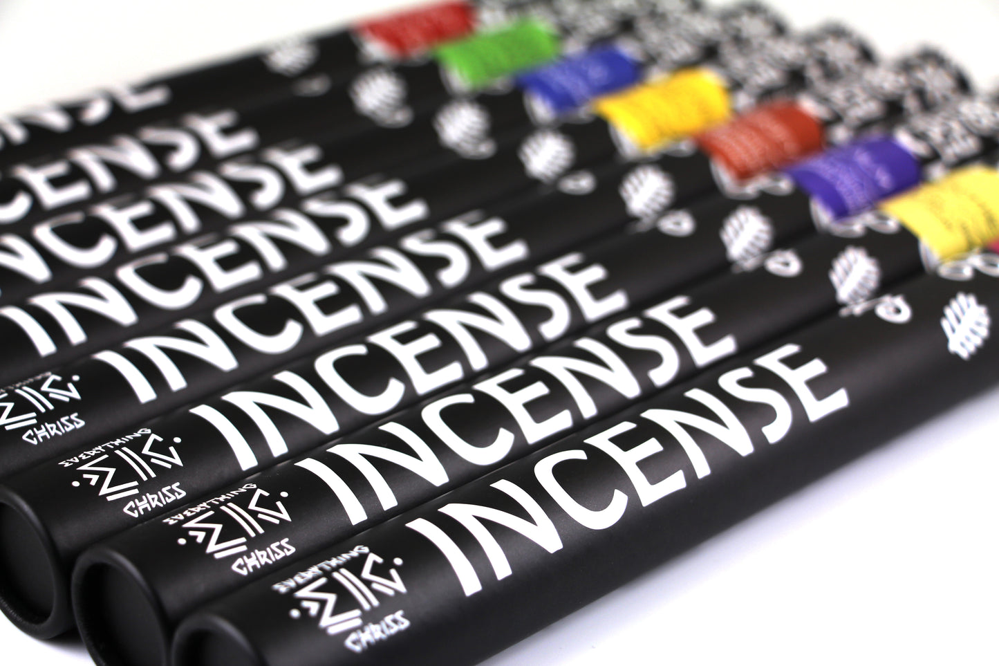 A collection of incense sticks with black  tube packaging and various colored labels laid flat, displayed in a tube-shaped arrangement.