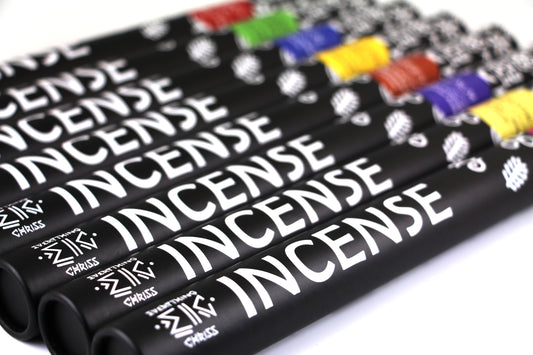 A collection of incense sticks with black  tube packaging and various colored labels laid flat, displayed in a tube-shaped arrangement.
